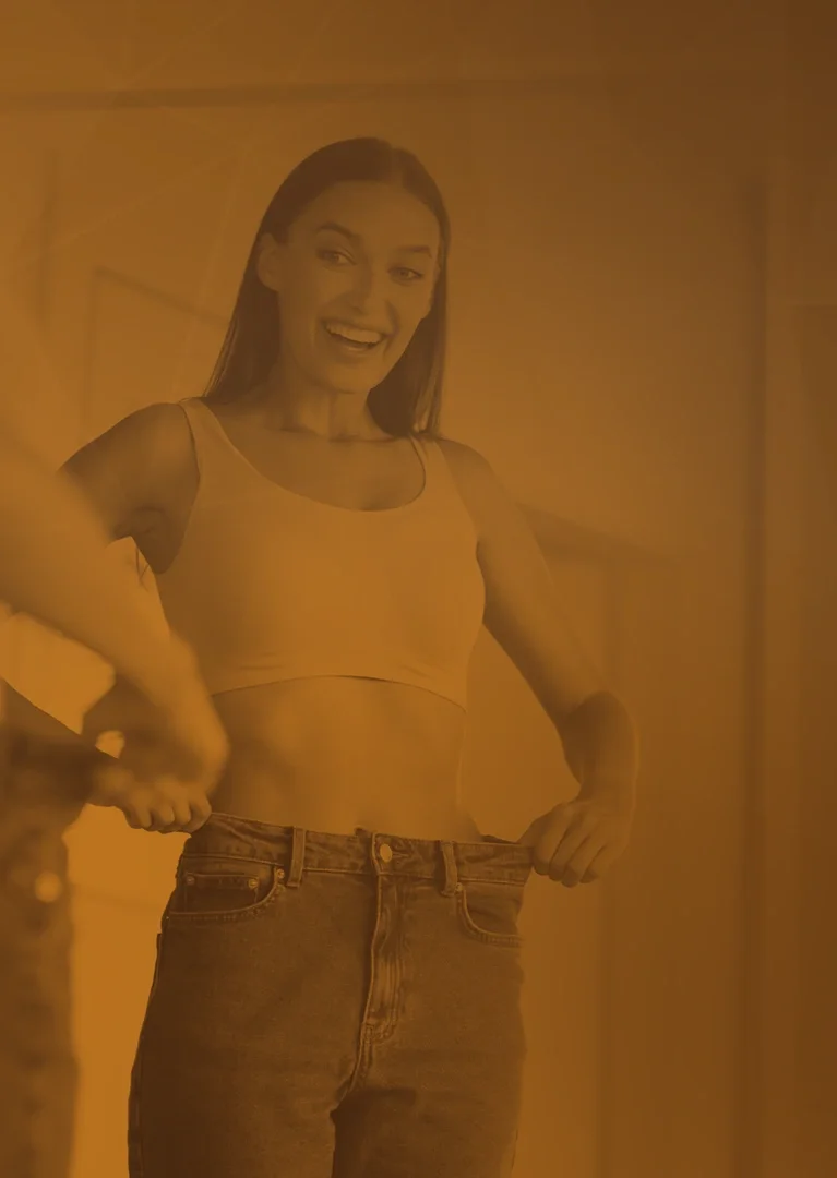 A woman who reached her weight-management goals shows off looser-fitting jeans
